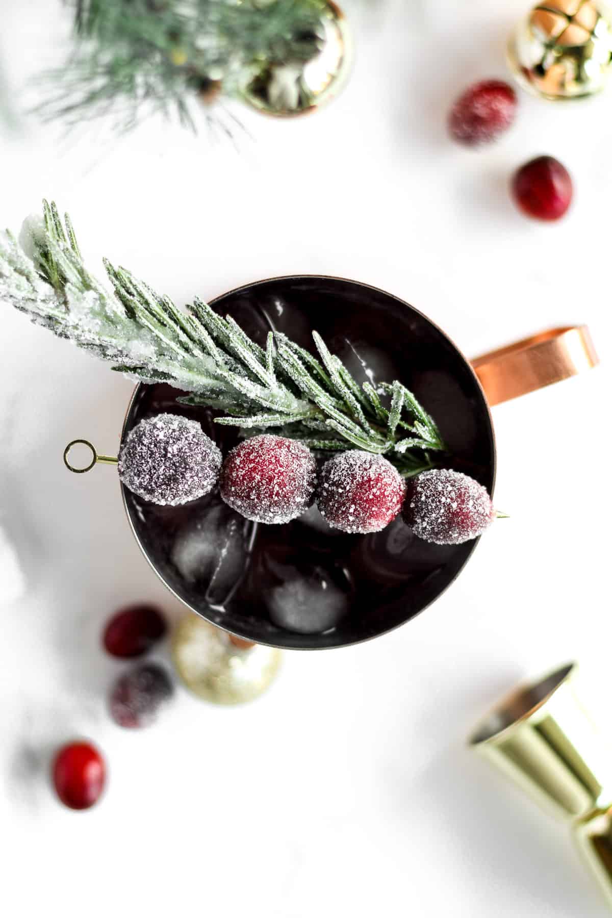 Christmas Moscow mule garnished with sugar-coated cranberries and rosemary.