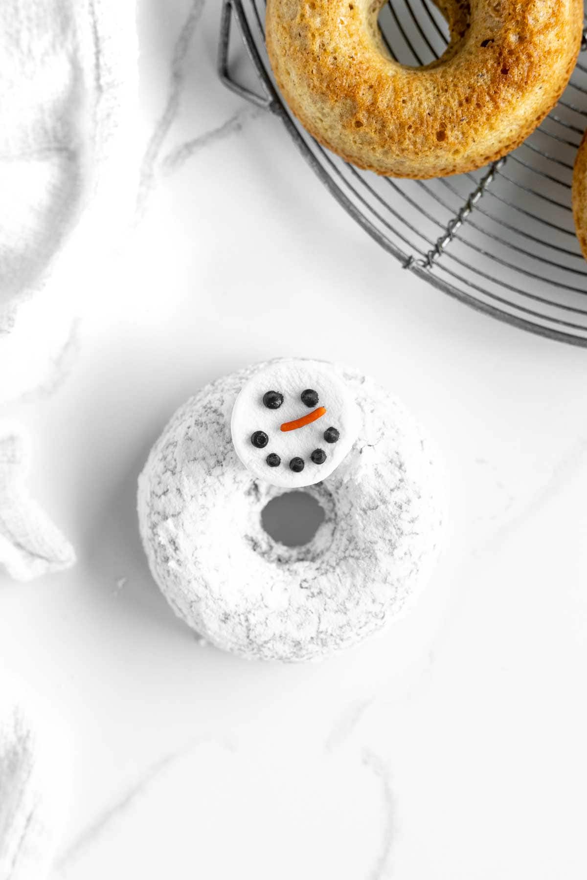 Snowman head decorated with black icing and orange sprinkle.