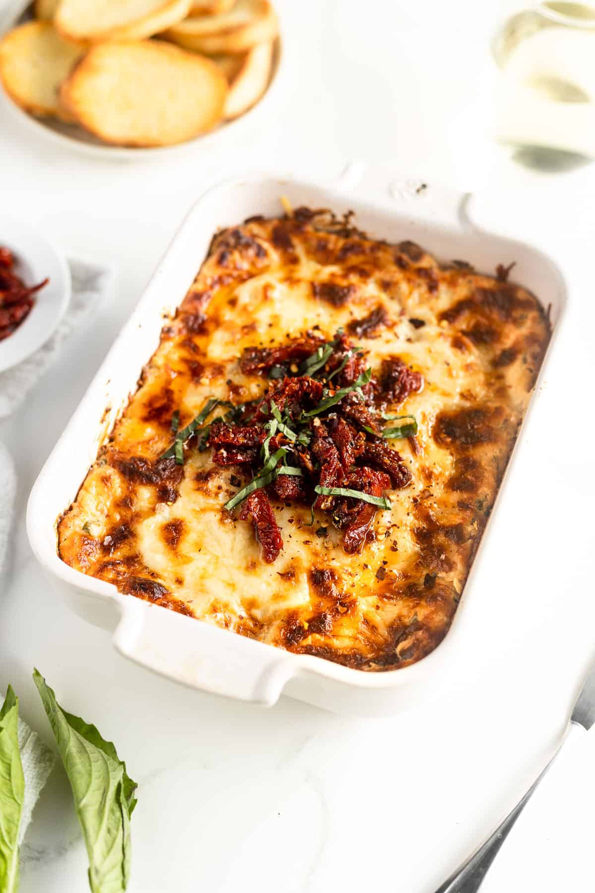Baked chicken dip topped with sun dried tomatoes and basil.