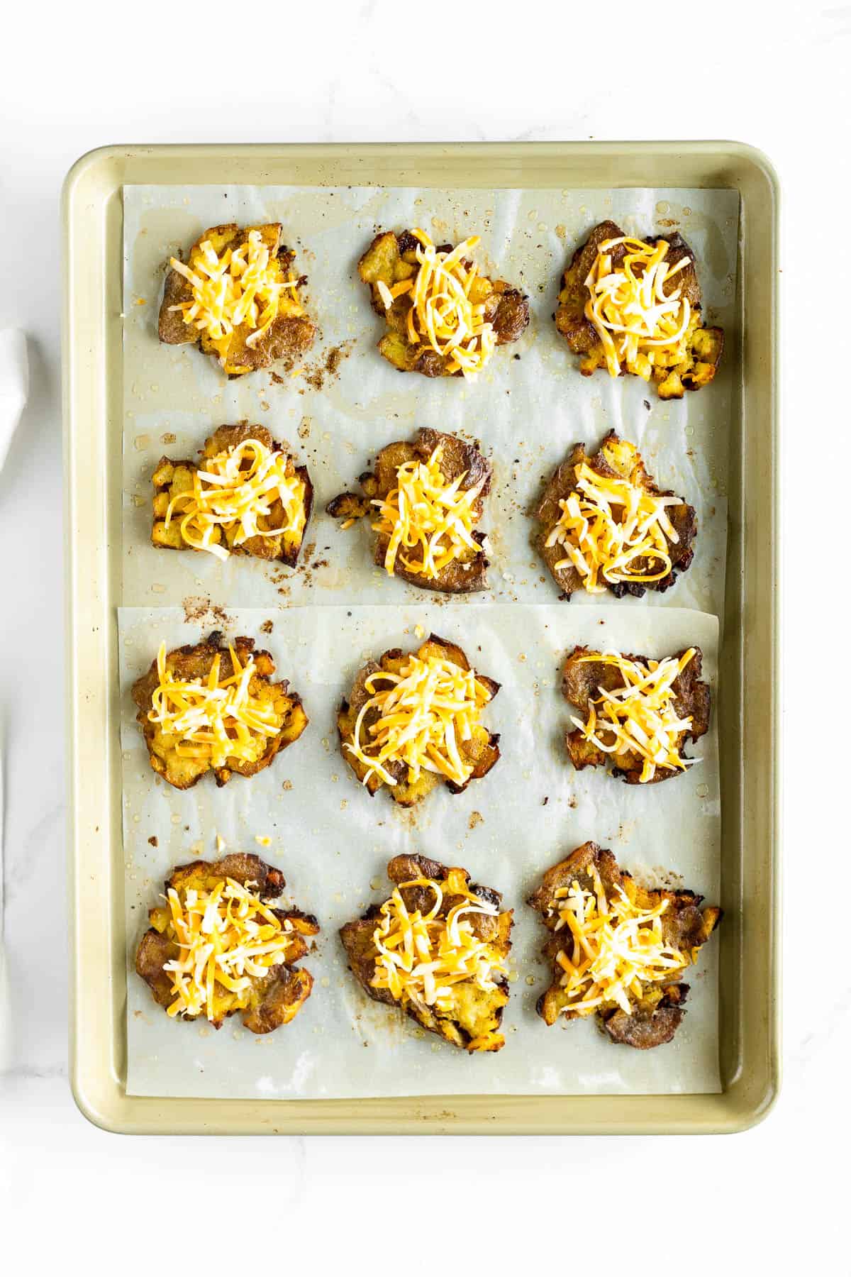 Cheese added to baked smashed potatoes.